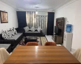 مبلمان مشکی رنگ و تلویزیون وپرده های کرمی مشکی سالن نشیمن آپارتمان در بندرعباس
