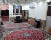 فرش قرمز و پشتی و میز تلویزیون و کمد سالن نشیمن خانه روستایی در بندرلنگه1