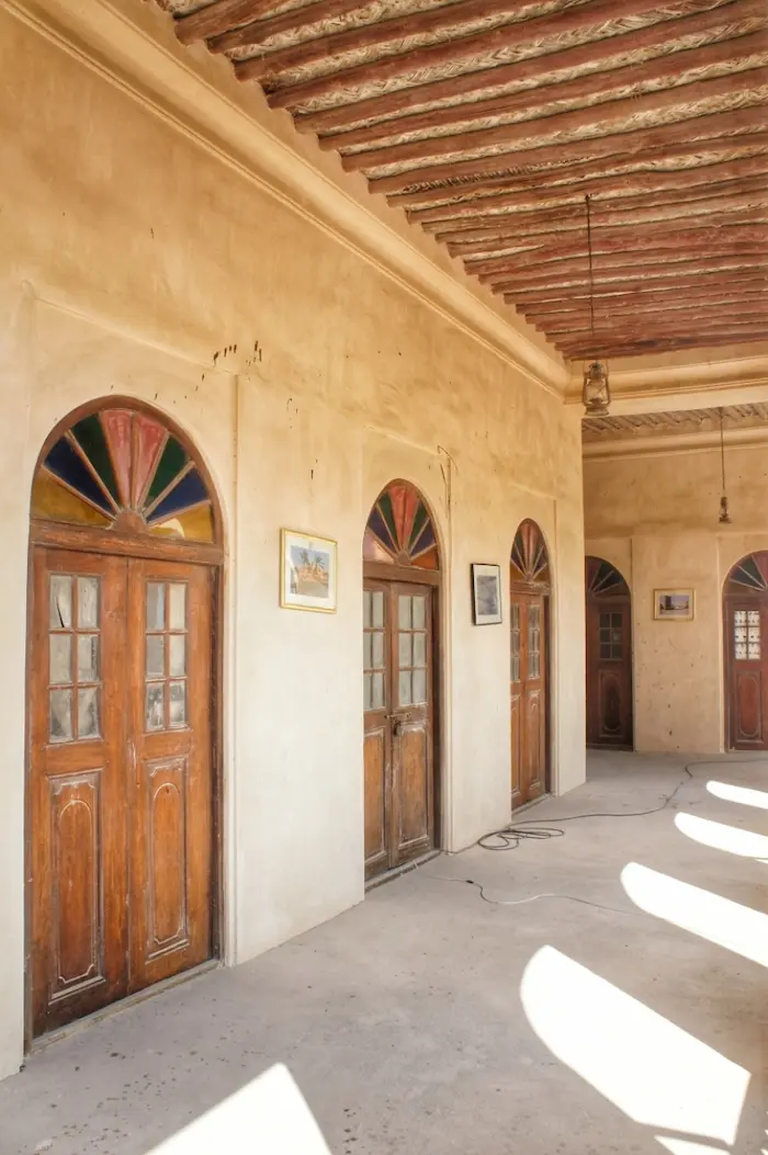 زاویه دیگر از درب های چوبی قدیمی قهوه ای و دیوار های گچی در عمارت فکری 13251543