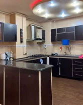 کابینت های قهوه ای و هود و سقف نور پردازی شده با نور قرمز و سفید آشپزخانه آپارتمان در بندرجاسک