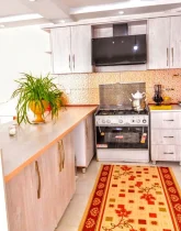 آشپزخانه با کابینت های چوبی، یخچال، هود و گل های خانه ویلایی در بندرلنگه 4588654