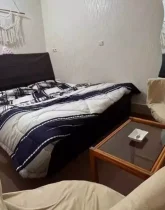 تخت خواب با روتختی سفید سرمه ای و صندلی اتاق خواب آپارتمان در بندر جاسک